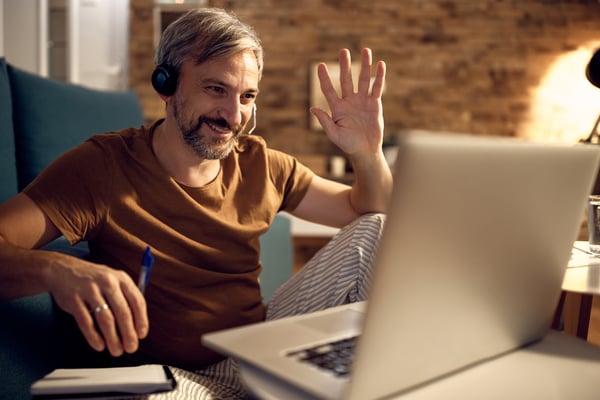 A guy sitting on the couch while he earn money online as a online tutor.