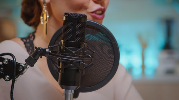 A woman in front of a microphone recording a podcast, a way to make money at home in canada