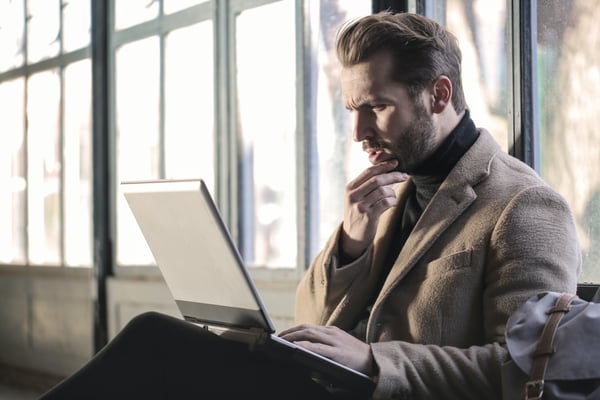 Photo from blog post on passive income ideas shows a man pondering something on his laptop