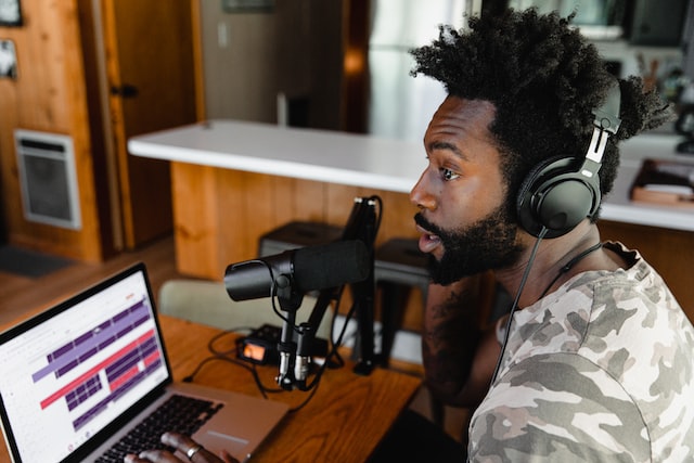 Photo shows a person sitting across from a laptop, speaking into a microphone and wearing headphones. This is an example from the section on starting an online business in Canada with a podcast.