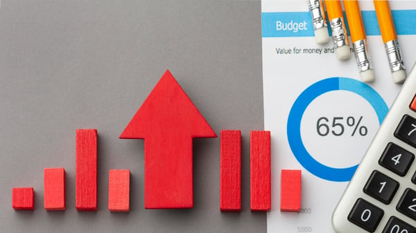 Photo from article that explains what is profit margin and why it is important shows a few wooden blocks on a table, representing a bar chart, next to a calculator and four pencils.